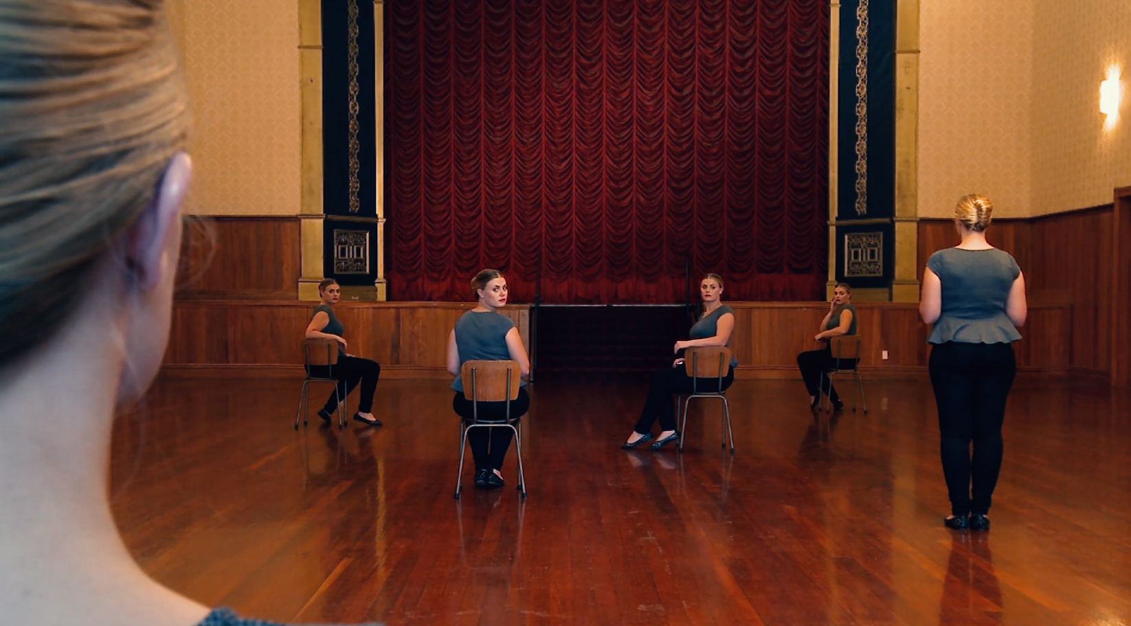 images of six identically dressed women in an auditorium