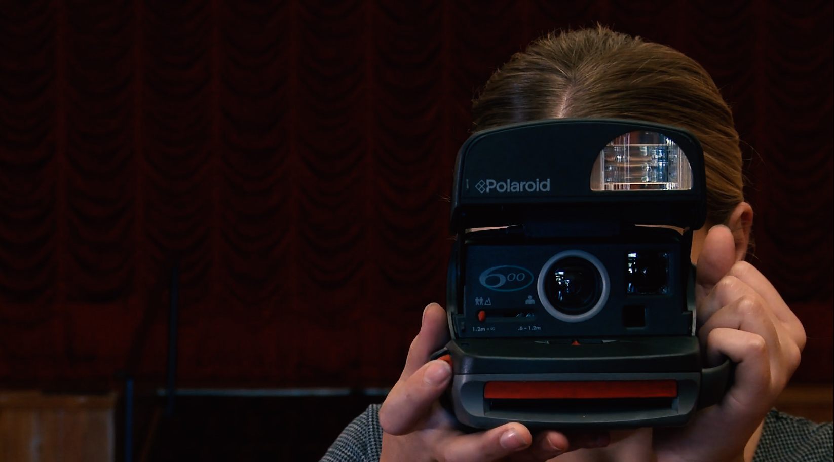 image of a woman taking photographs with a polaroid camera obscuring her face