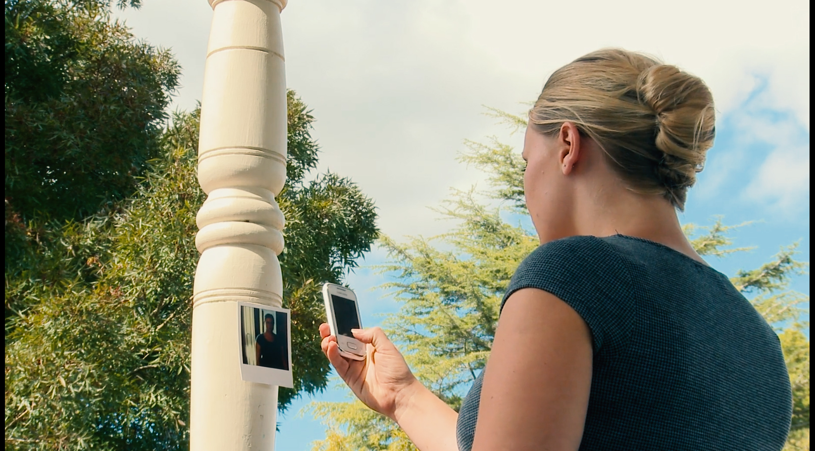 image a woman using a smartphone to photograph a printed picture of herself